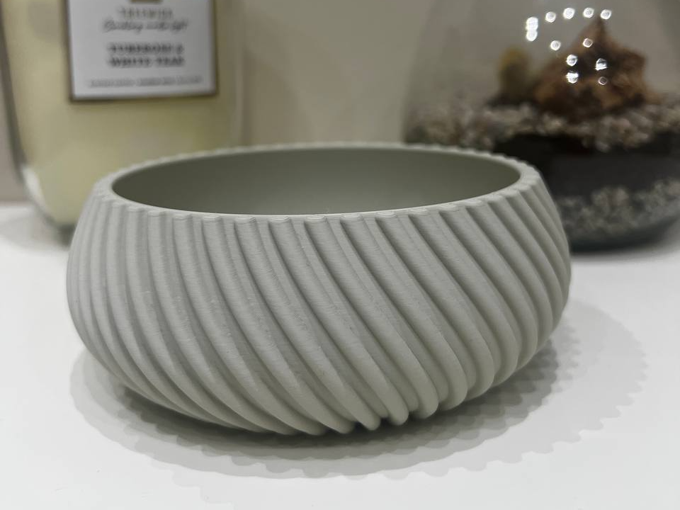 Vaciabolsillos impreso en 3D presentado desde un lado con compartimentos visibles y un fondo neutro