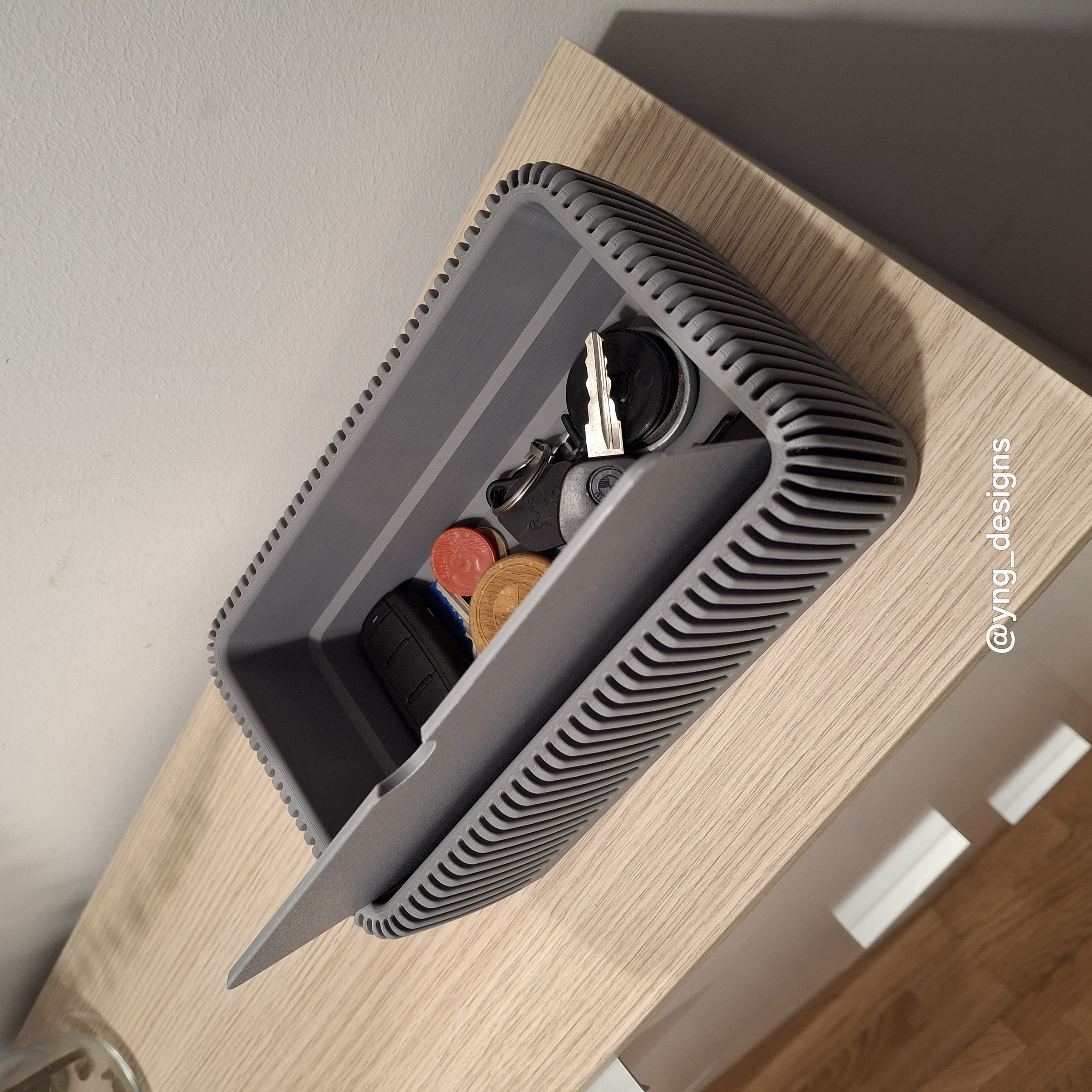 Vaciabolsillos impreso en 3D presentado desde un lado con compartimentos visibles y un fondo neutro